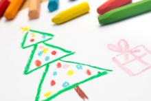 A drawing of a christmas tree with crayons in the background