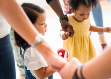 Toddlers holding hands with parents