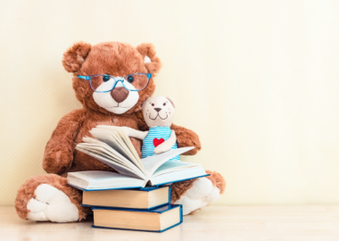 Two teddies reading a pile of books