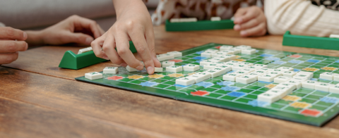 Hands playing scrabble tiles