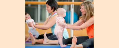 Two parents holding babies during yoga class